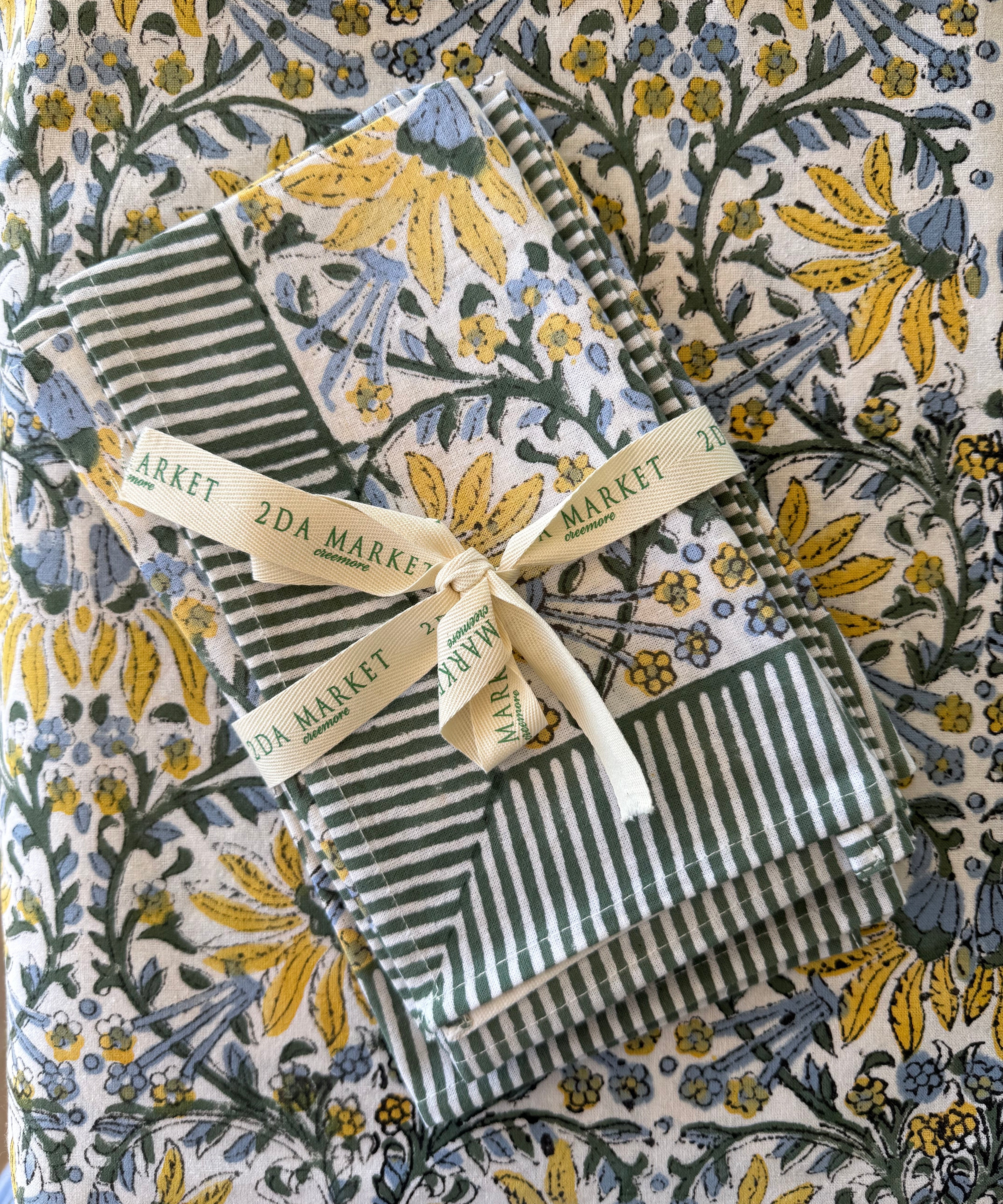Green and white striped fabric with a yellow ribbon on a floral-patterned background