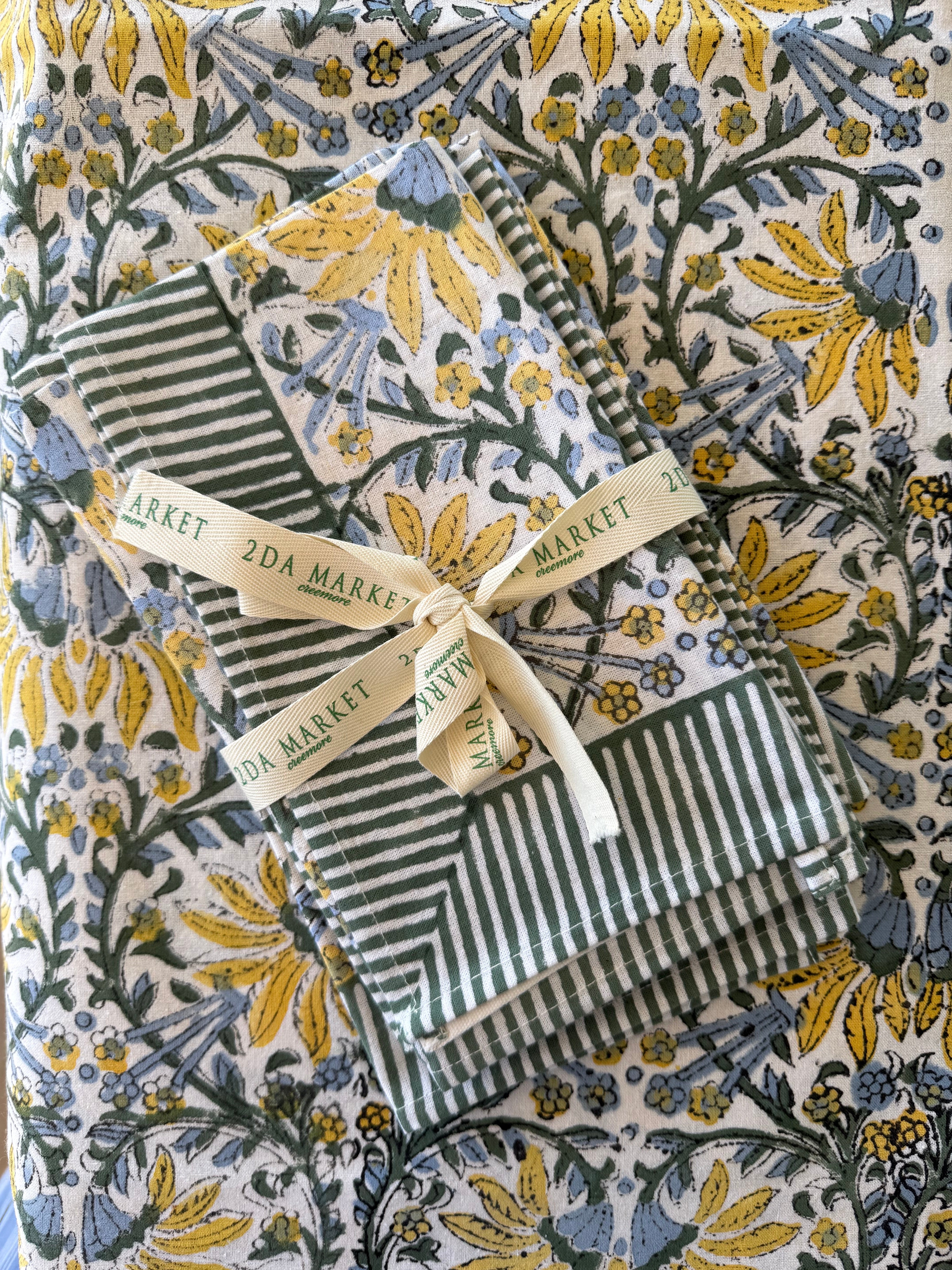 Green and white striped fabric with a yellow ribbon on a floral-patterned background